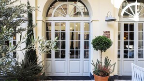 A building entrance with white doors and arched windows, a potted plant, and a sign indicating a restaurant. - Ecole St Pierre Hotel (Istanbul)