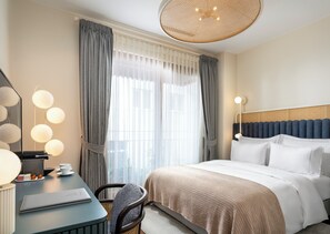 Una habitación de hotel con una cama, un escritorio con una computadora portátil, una silla y un ventanal con cortinas.