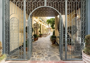 A stone-paved courtyard with a metal gate, potted plants, and a covered walkway. - Ecole St Pierre Hotel (Istanbul)