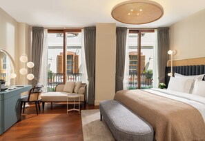 A hotel room with a bed, a desk, a chair, a bench, and a large window with curtains. - Ecole St Pierre Hotel (Istanbul)