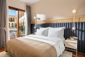 A hotel room with a large bed, a nightstand, a lamp, and a view of a building outside. - Ecole St Pierre Hotel (Istanbul)