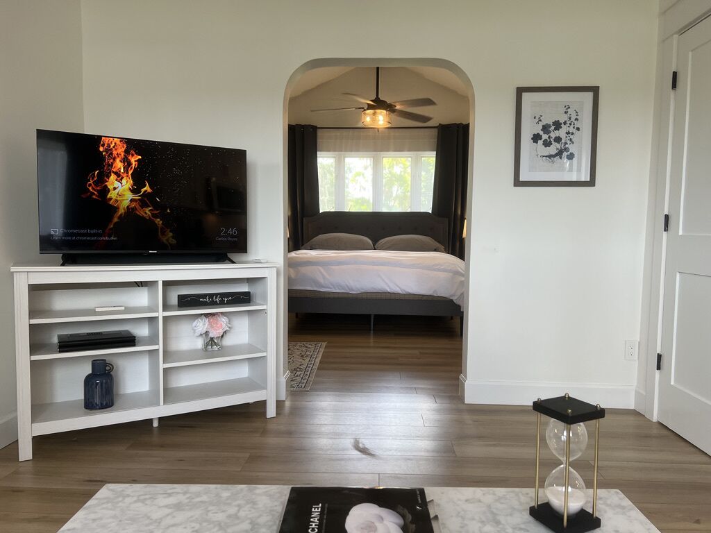 Un dormitorio con cama, televisor, estante y puerta.