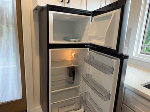 A modern kitchen with a built-in refrigerator, clear shelving, and a window providing natural light.