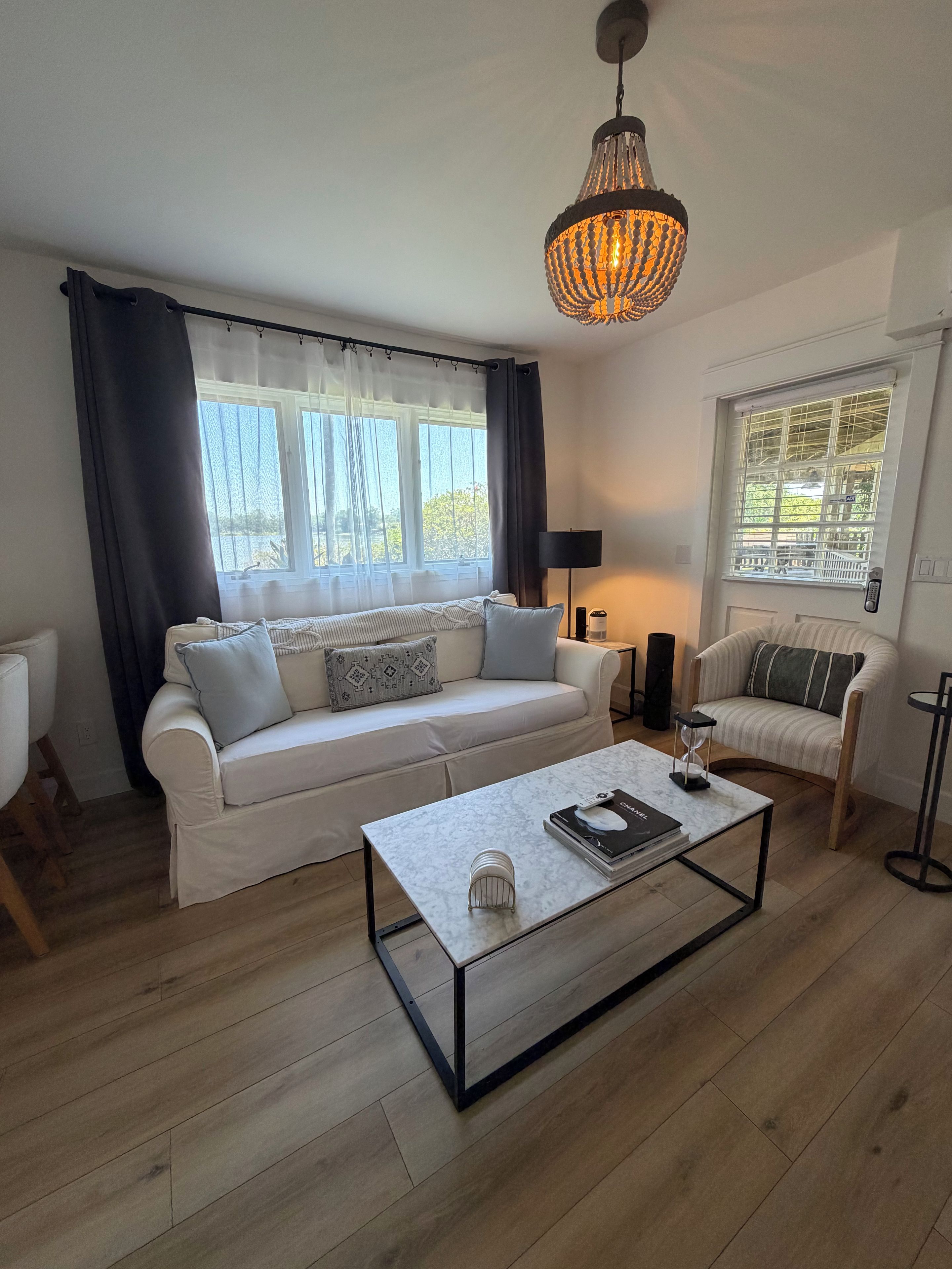 Un salon moderne avec un canapé blanc, une table basse et un luminaire suspendu.