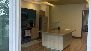 A modern kitchen with a central island, built-in appliances, and a wooden floor.
