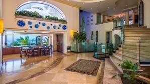 A spacious lobby with a large seating area, a staircase, and a view of the ocean. - P V South Shore Luxury Accommodations (Puerto Vallarta)