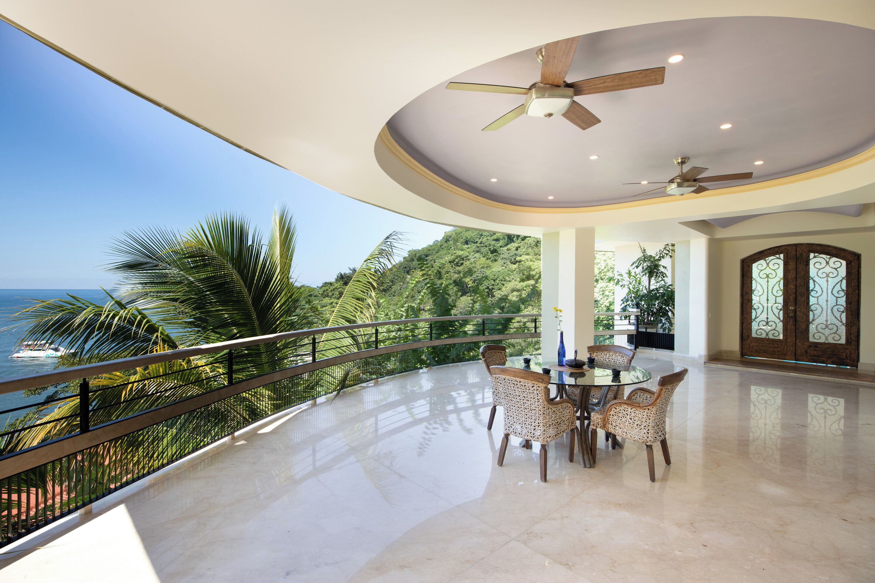 Un amplio balcón con una mesa y sillas para comer, con vista a un paisaje marino.