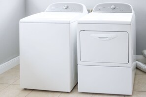 Deux machines à laver à chargement frontal, de couleur blanche, sont placées dans un coin d’une pièce dont le sol est recouvert de carreaux de couleur claire.