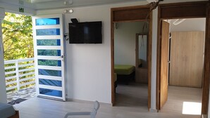 A room with a bed, a TV mounted on the wall, a wooden wardrobe, and a door leading to another room. - Comfortable and safe apartment 3 minutes walk to the beaches (San Andrés y Providencia)
