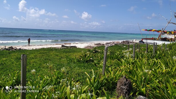A beach with a person walking, a boat, and a colorful umbrella. - Comfortable and safe apartment 3 minutes walk to the beaches (San Andrés y Providencia)