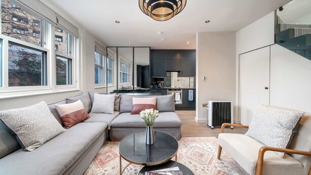 Ein modernes Wohnzimmer mit einem Ecksofa, einem Couchtisch und Blick auf die Küche und den Essbereich.