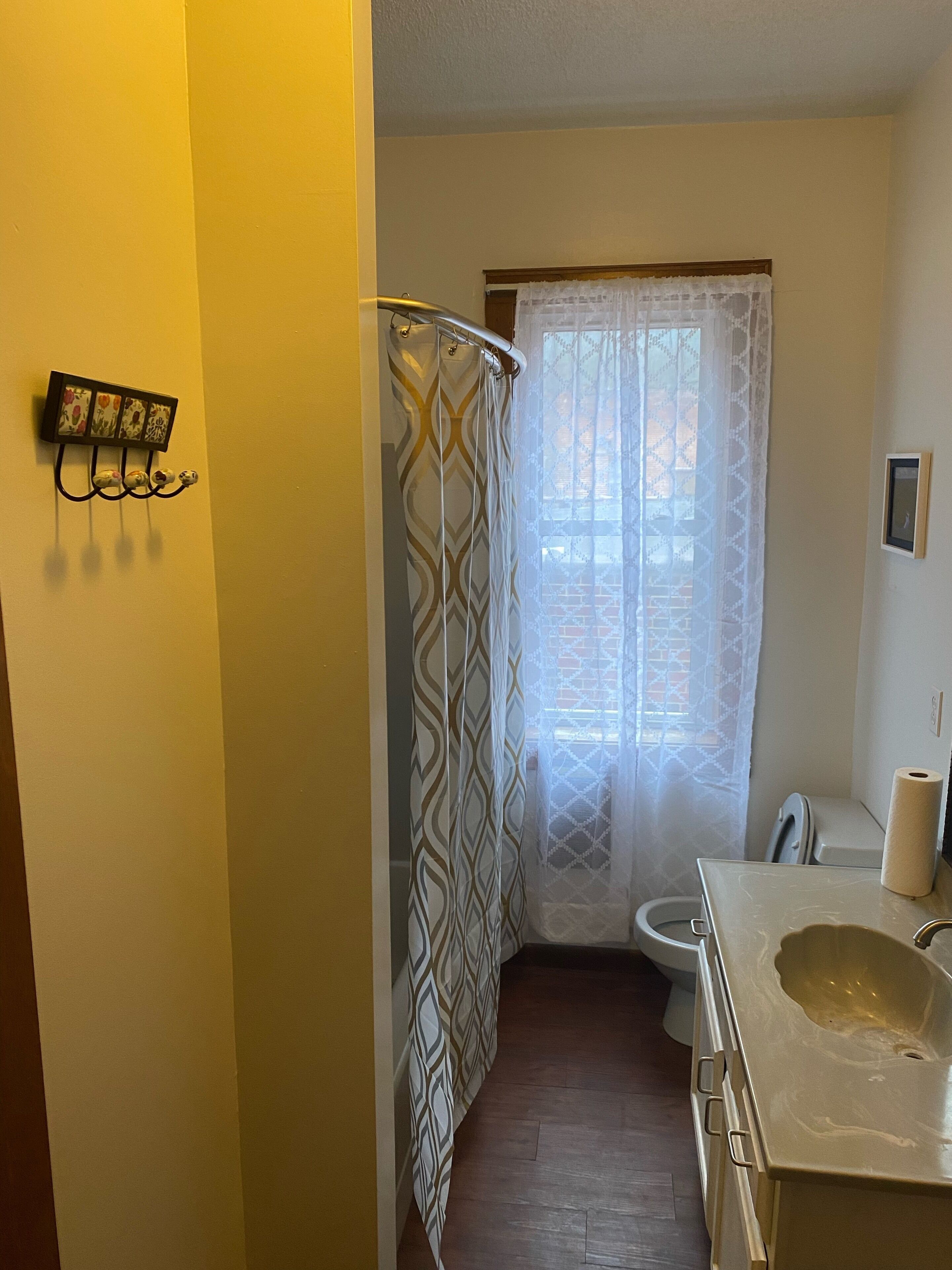 A narrow bathroom with a shower curtain, toilet, and sink.