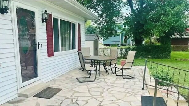 A patio with stone flooring, a table, and chairs.