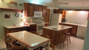 A compact kitchen with wooden cabinets, a central island, and a dining area with chairs.