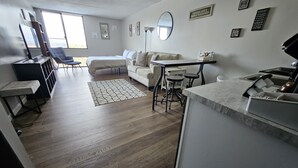 A modern living room with a sofa, a dining table, and a kitchen area.