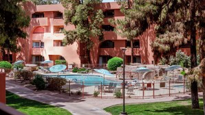 Un hotel con piscina, mobiliario exterior y un patio amurallado.