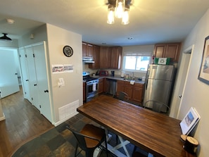 A kitchen with wooden cabinets, a stainless steel refrigerator, a stove, and a dining table with chairs. - Cozy Remodeled Cabin in Central Nederland (Nederland)