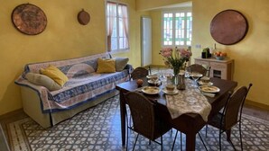 A dining area with a table set for four, a sofa, and a decorative ceiling light. - Superba Vista by Interhome (Valloria)