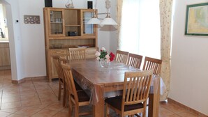 Un coin repas avec une table et des chaises en bois, un meuble avec des portes en verre et un vase rempli de fleurs.