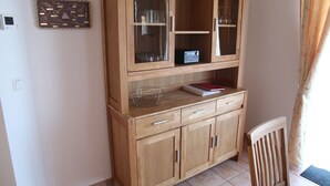 Un meuble en bois avec des portes en verre, une radio et un livre posé sur le dessus.
