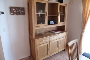 Un mueble de madera con puertas de vidrio, una radio y un libro encima.