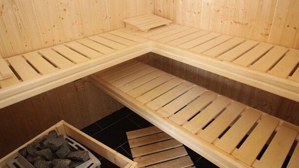 Un sauna avec des bancs en bois et un récipient rempli de pierres.
