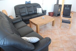 A living room with a black leather sofa, a wooden coffee table, a wooden chair, and a fireplace.