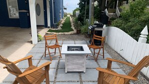 A patio with a table and four wooden chairs, surrounded by a white fence and a garden path. - Beachfront Getaway, Dolphin Suite, 🐶 💙 (Norfolk)