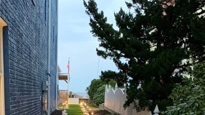 A landscaped garden with a stone border, a grassy path, and a building on one side. - Beachfront Getaway, Dolphin Suite, 🐶 💙 (Norfolk)