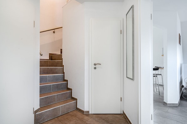 A staircase with brown tiles leading to a white door.