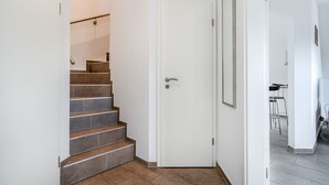 Una escalera con baldosas marrones que conduce a una puerta blanca.