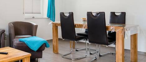 Una habitación con un sofá de cuero marrón, una mesa de madera y tres sillas negras.