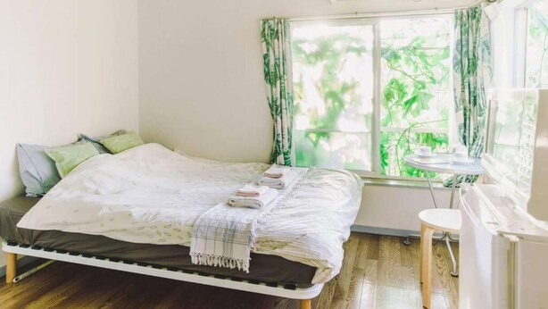 A bedroom with a bed, a bedside table, and a window with curtains. - Home WIFI & Compact & Tranquil Apt with LOFT! (杉並区)