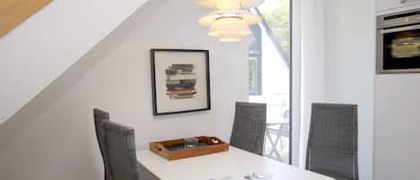 A modern kitchen with a white countertop, a built-in oven, and a hanging light fixture.