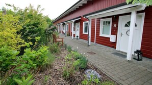 Une rangée de bâtiments rouges aux portes blanches, numérotés 35, et un banc au premier plan.