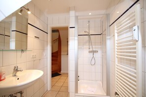Een moderne badkamer met een wit wastafelmeubel, spiegel en douche.