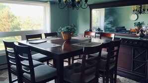 A dining area with a table set for four, surrounded by chairs. A chandelier hangs above the table, and there is a window providing natural light. - Beautiful upper unit countryside large cozy rooms near Niagara Falls (Welland)