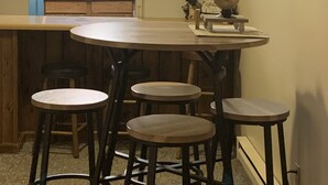 Una cocina con una mesa de madera y taburetes de bar, un refrigerador, un ventanal y un adorno de cuernos de ciervo.