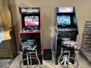 Due cabinati arcade, uno con Mortal Kombat e uno con Asteroids, con sgabelli davanti.