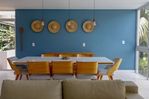 A dining area with a white table and wooden chairs, blue walls, and hanging light fixtures.