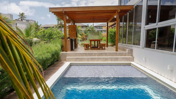 A swimming pool with a wooden pergola and a table and chairs nearby. - WONDERFUL HOUSE - HIGH WALL/ PORTO DE GALINHAS (IPojuca)