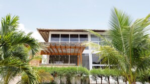 A modern house with a wooden pergola, large windows, and lush tropical plants. - WONDERFUL HOUSE - HIGH WALL/ PORTO DE GALINHAS (IPojuca)