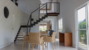 A spacious interior with a staircase, wicker furniture, and large windows. - WONDERFUL HOUSE - HIGH WALL/ PORTO DE GALINHAS (IPojuca)