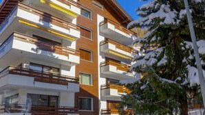 A multi-story building with balconies, wooden railings, and large windows. - Mont-Blanc by Interhome (Zermatt)