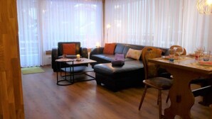 A cozy living room with a sofa, a coffee table, and a dining table set for two. - Mont-Blanc by Interhome (Zermatt)