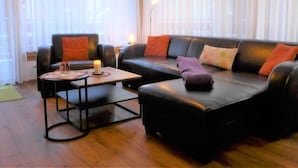 A modern living room with a black leather sofa, a small wooden coffee table, and a floor lamp. - Mont-Blanc by Interhome (Zermatt)