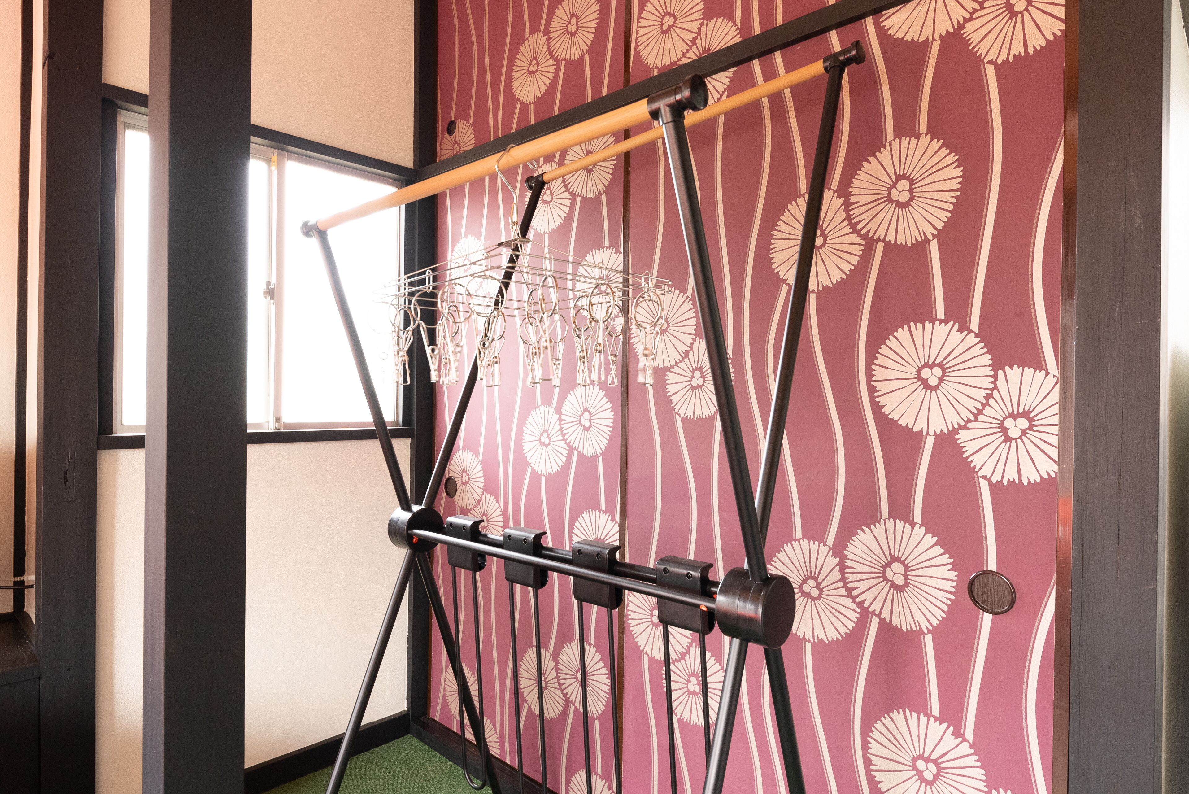 A room with a wall-mounted drying rack and a window with a view of the outside.