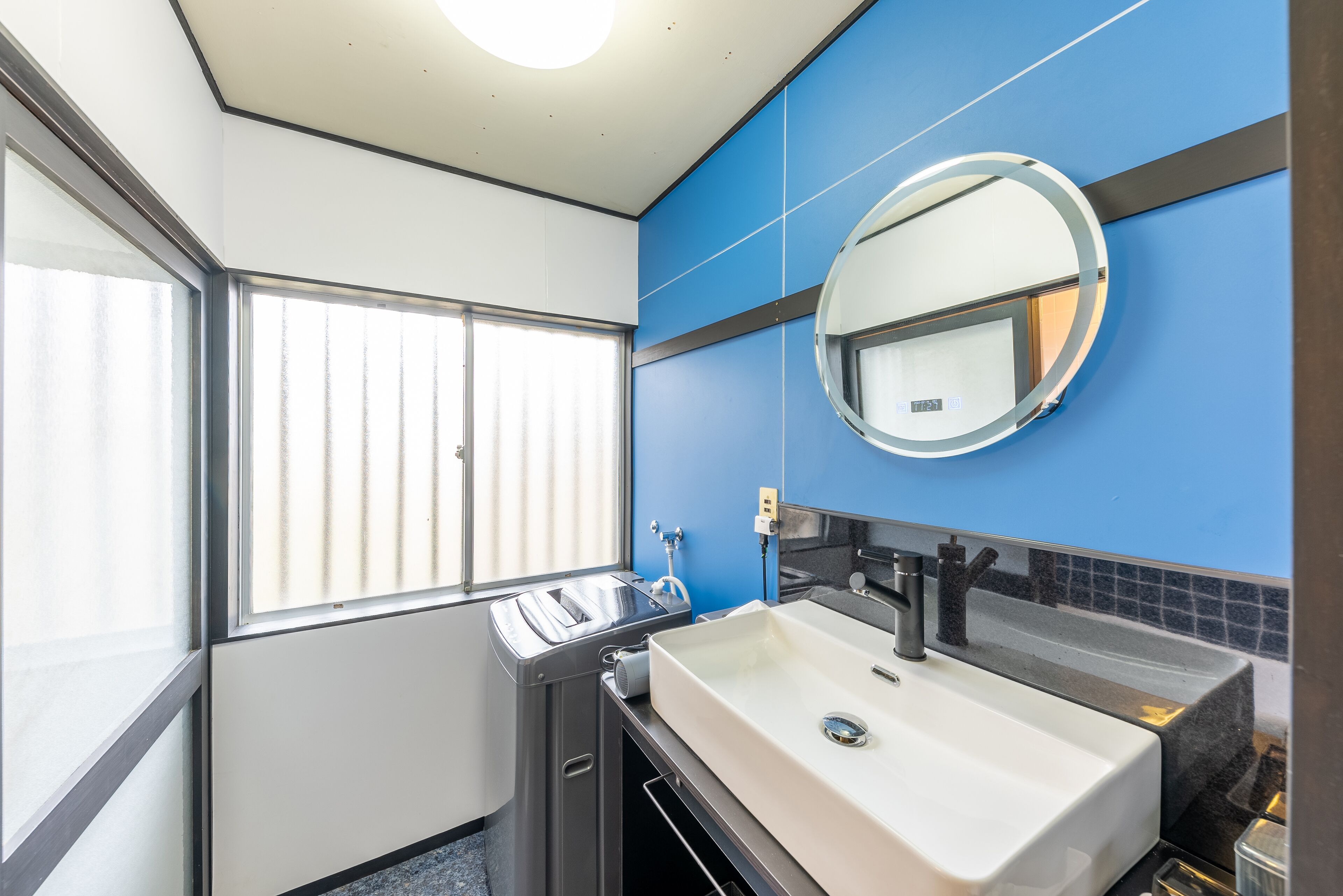 A modern bathroom with a large window, a sink, and a mirror.