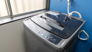 A compact, modern washing machine with a control panel, a water inlet, and a hose. - Izu Workation (Ito)