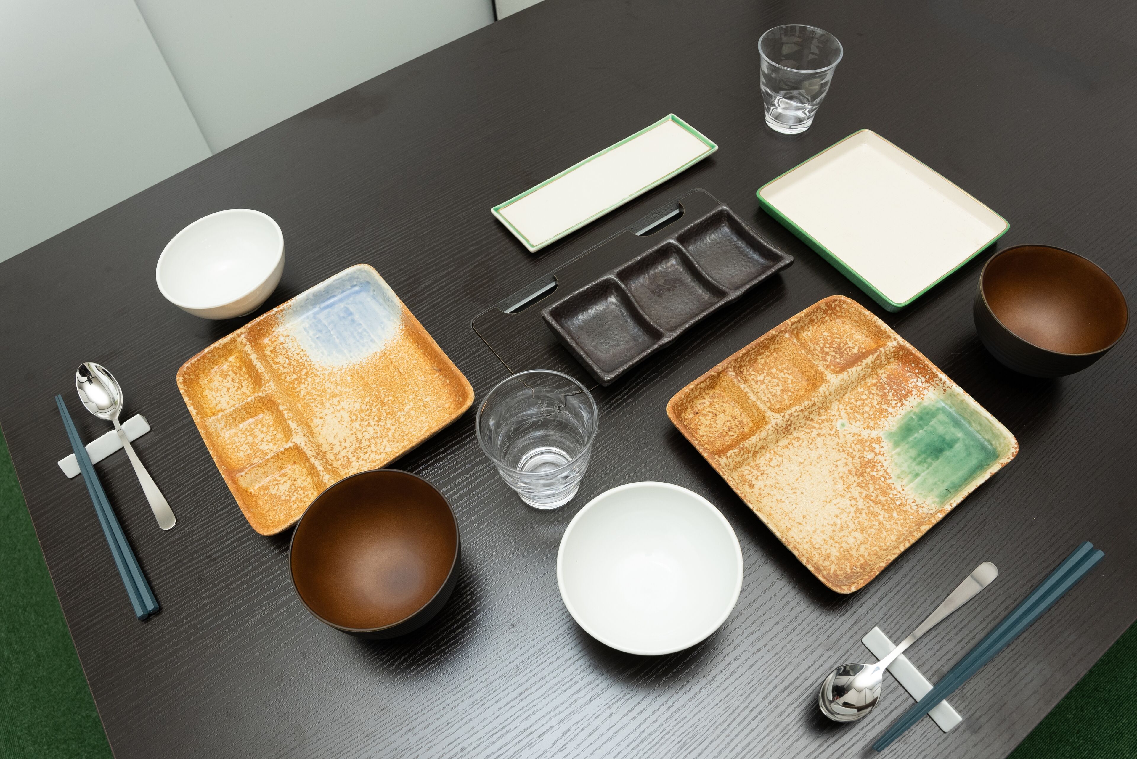 Une table à manger avec différents plats, bols, baguettes et une cuillère.